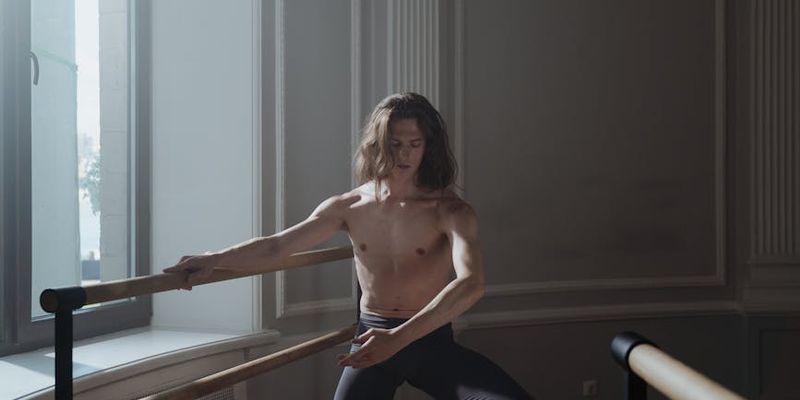 A man stretching his arms in a spacious, sunlit room.